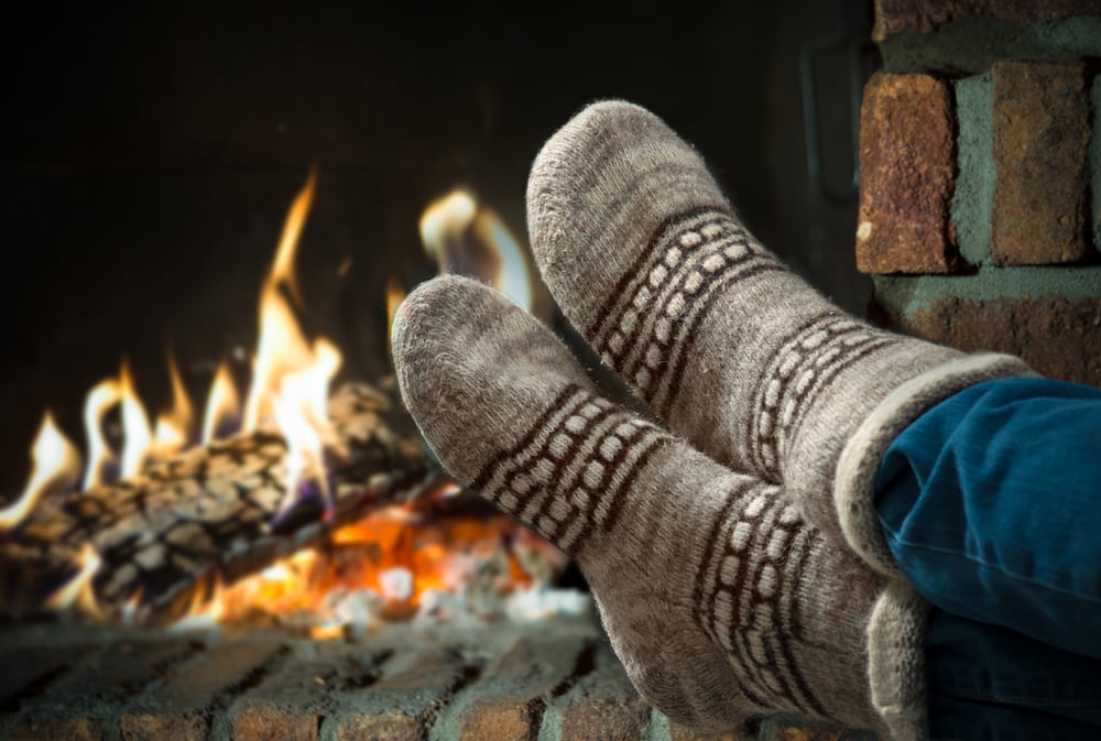Close-up-of-feet-in-cozy-socks-in-front-of-fireplace