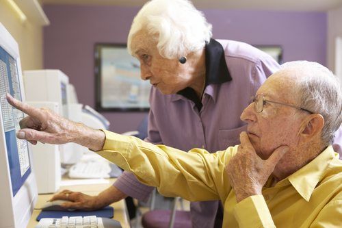 two seniors using a computer