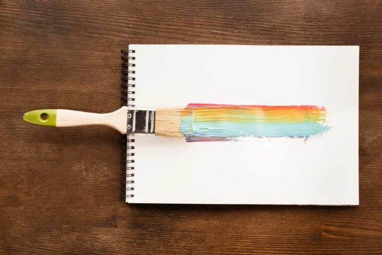Notepad-on-wood-table-paintbrush-creating-a-rainbow-streak