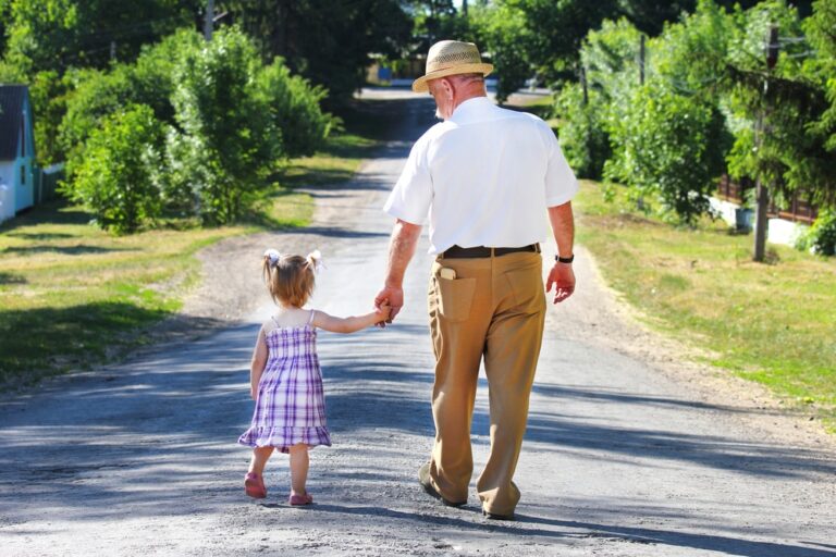Senior-man-and-granddaughter-walking-outside