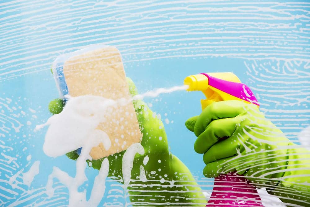 spraying-glass-with-cleaning-product-wiping-with-sponge