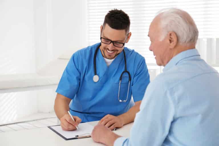 Young doctor smiling and talking with senior patient