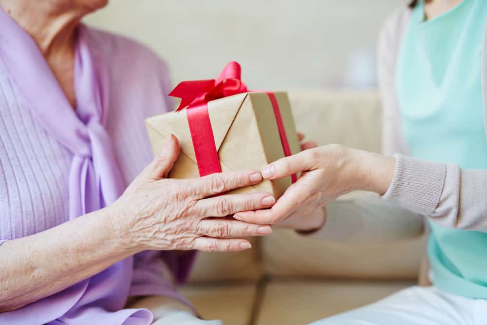 Younger woman handing senior woman a gift