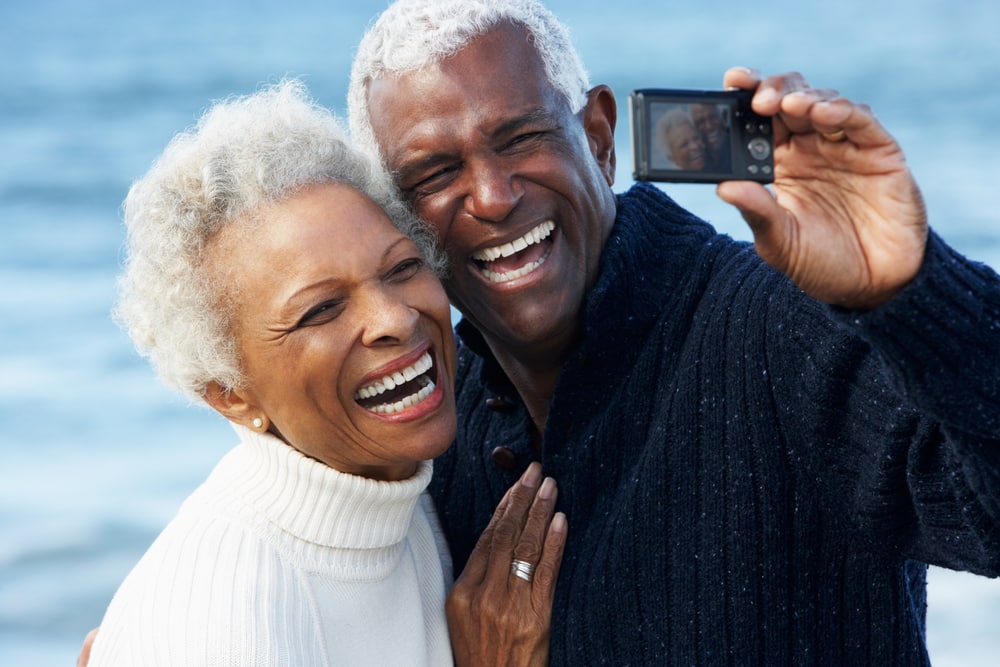 Senior couple laughing on beach in winter, taking a selfie