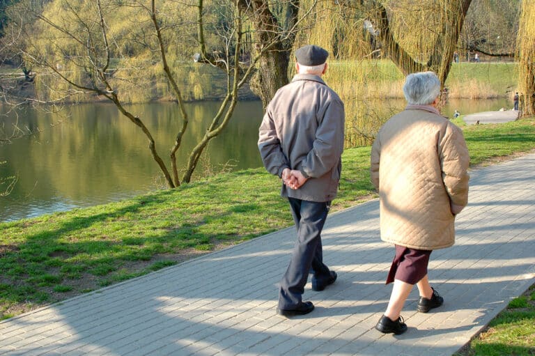 Two seniors walking in park in spring