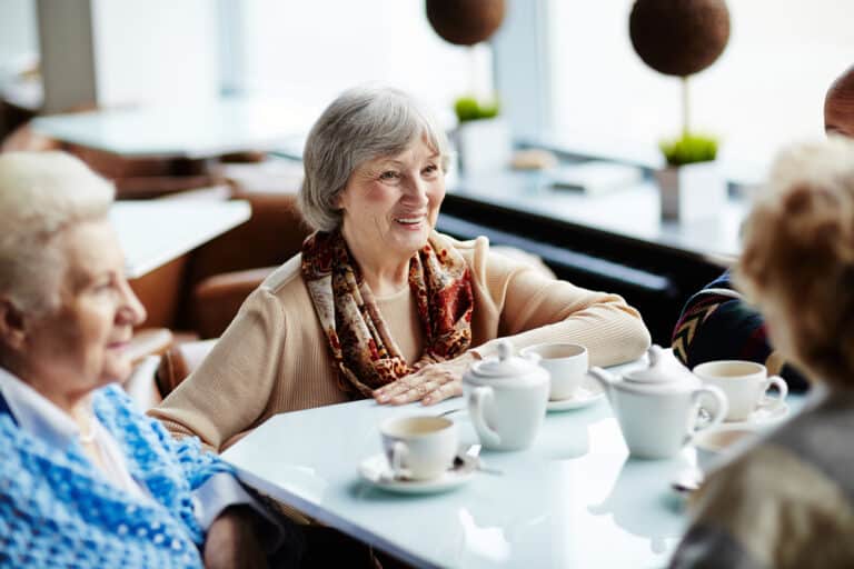 Smiling senior woman talking with friends over coffee