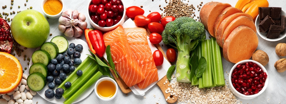 Spread of healthy foods including salmon, broccoli, nuts, berries, apples, etc
