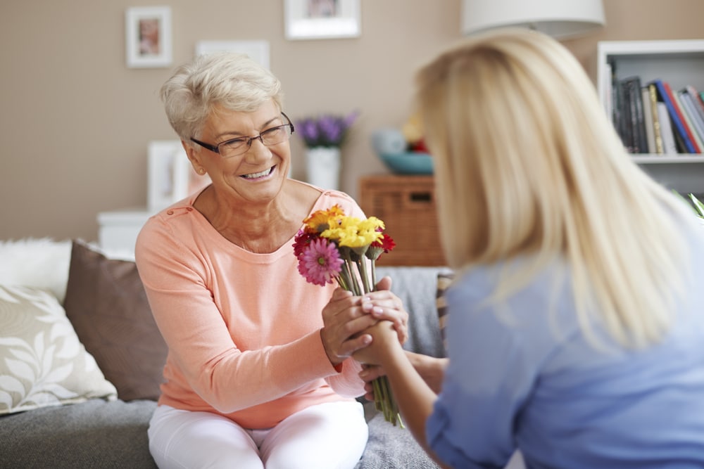 Smiling senior woman receiving flowers from younger woman