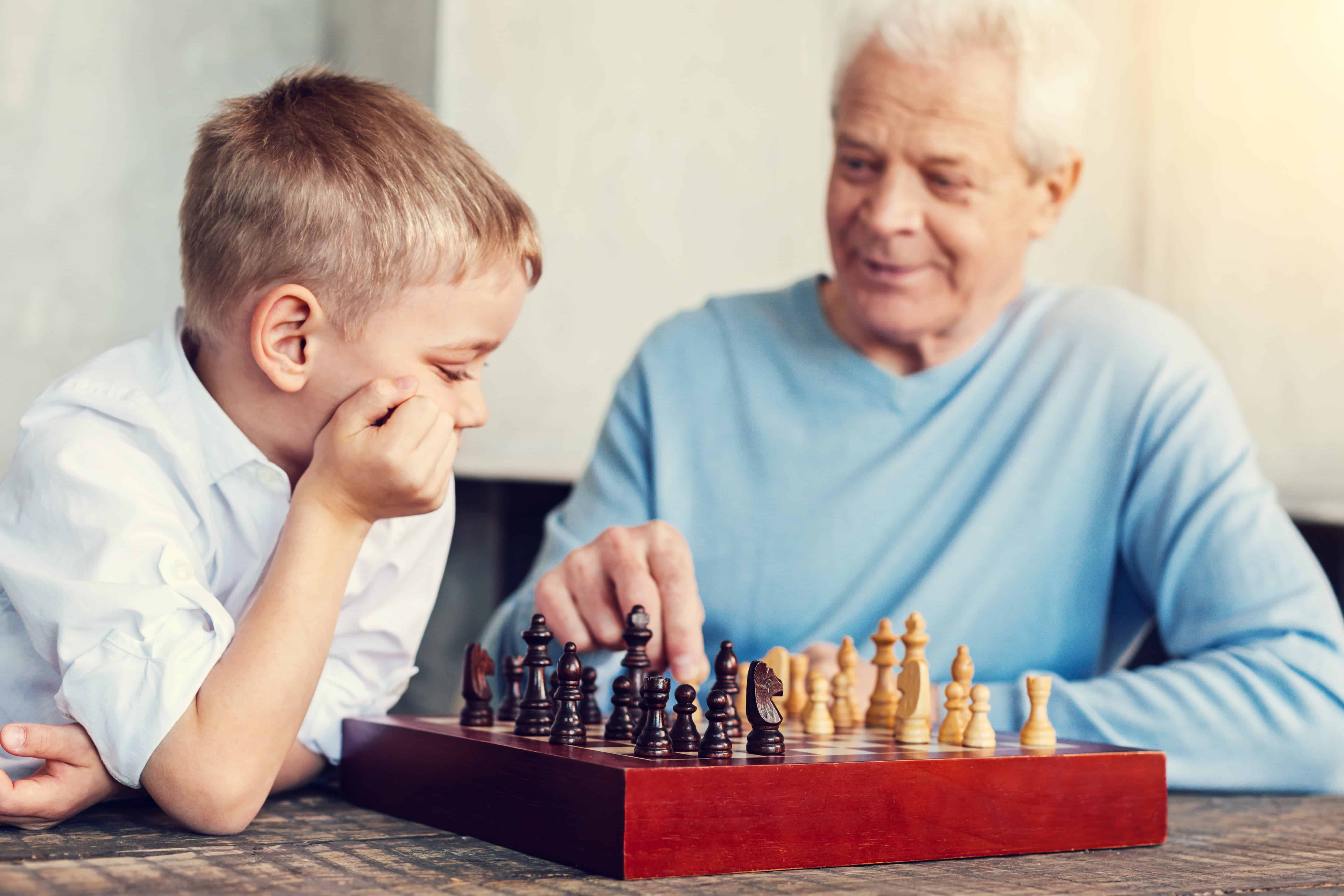 Young boy playing chess with his grandpa
