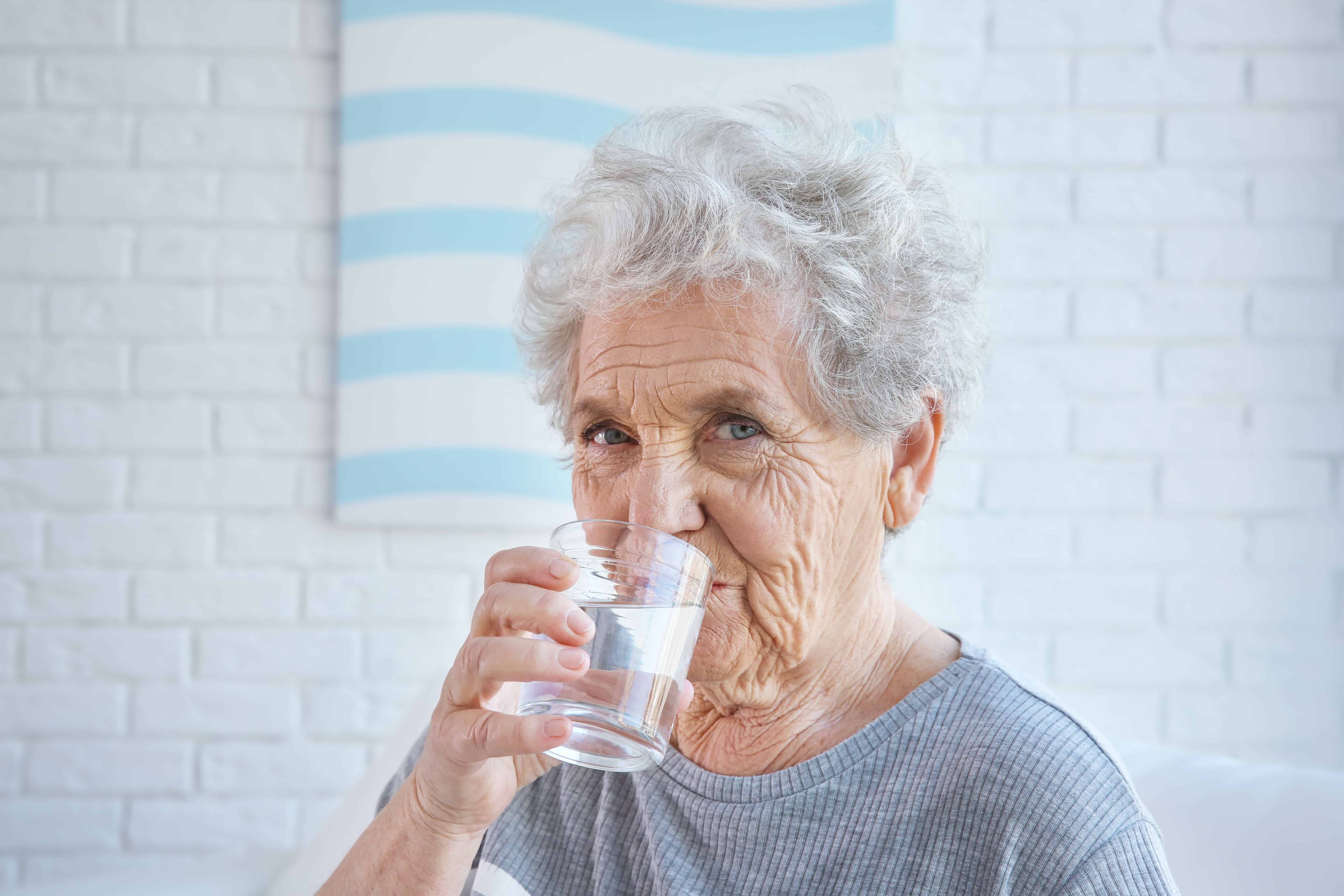 senior woman drinking water indoors