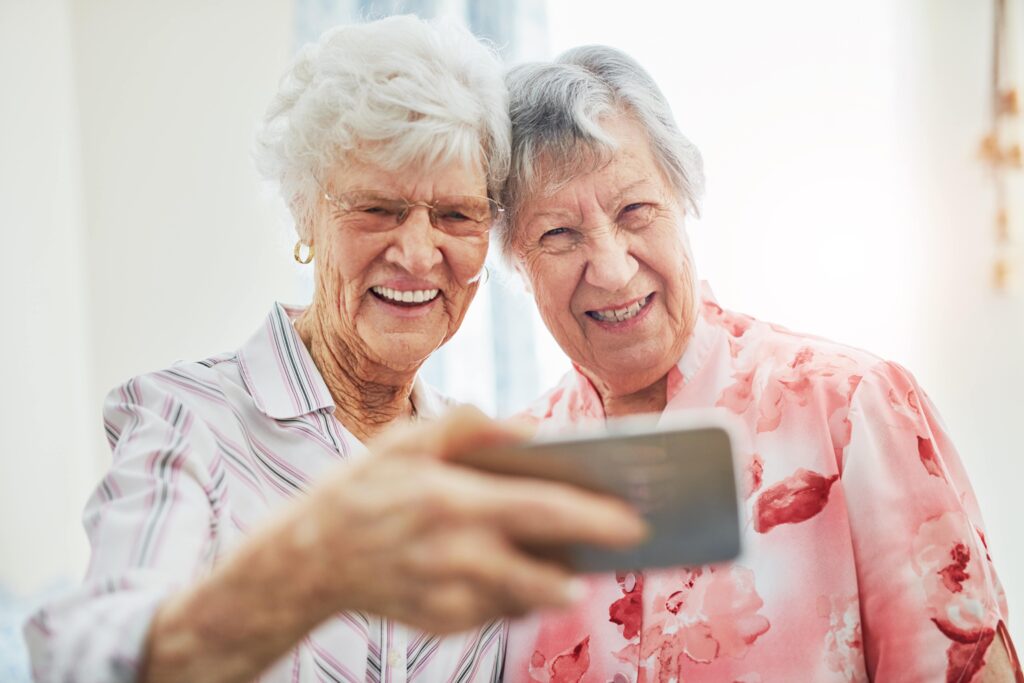 Two senior female friends taking a selfie together, smiling