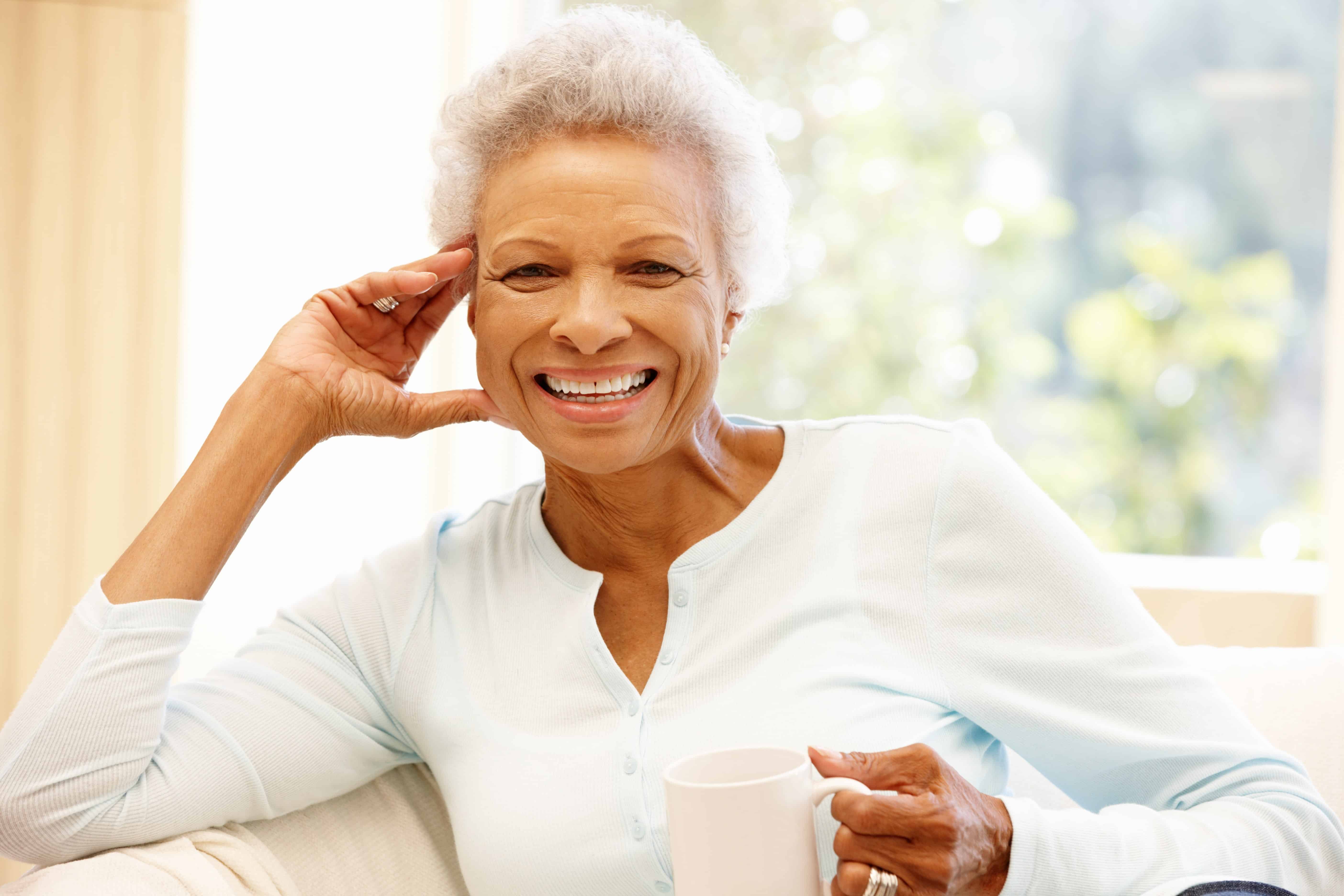 Portrait of smiling senior woman in front of window