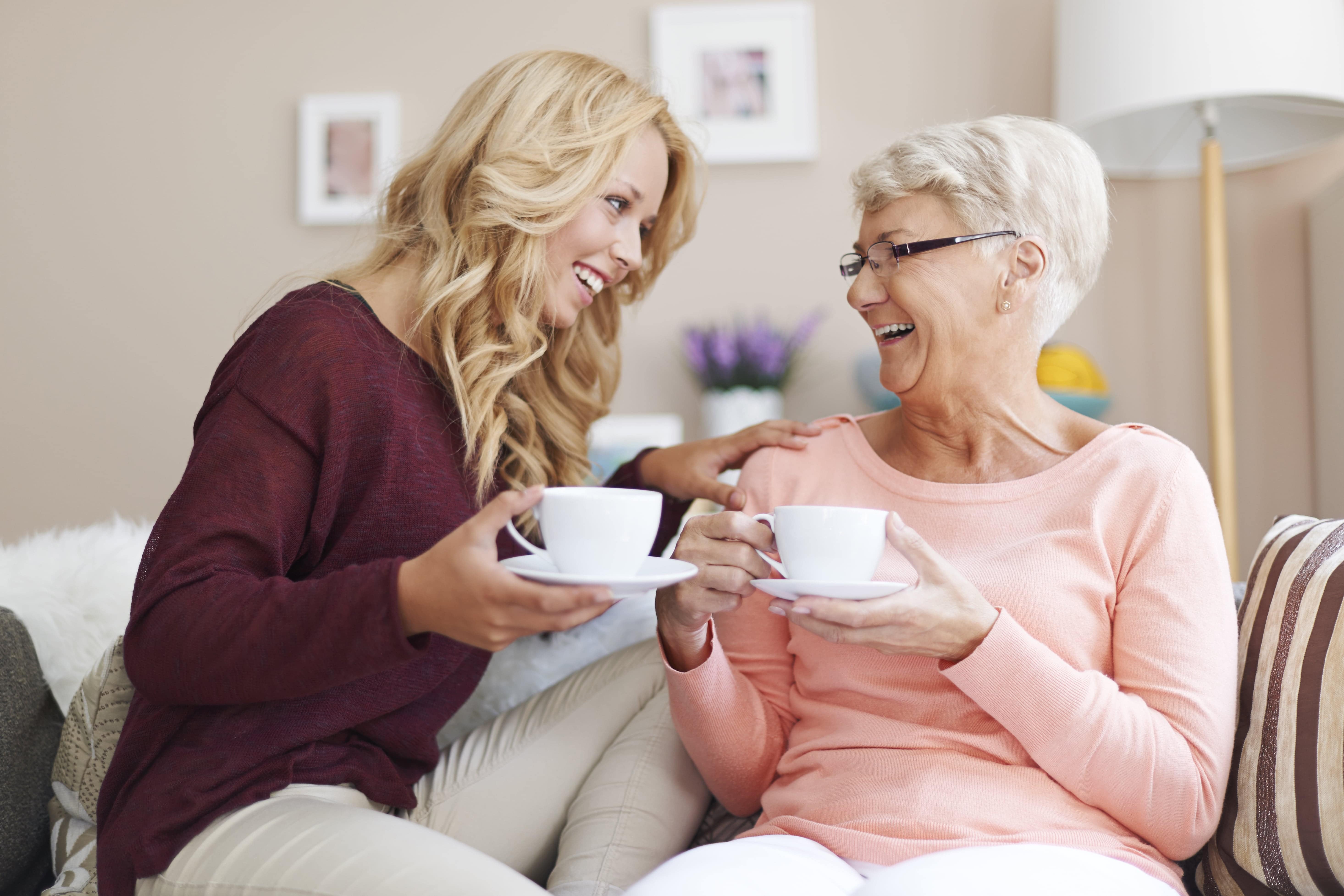 Young woman and grandma drinking tea and smiling